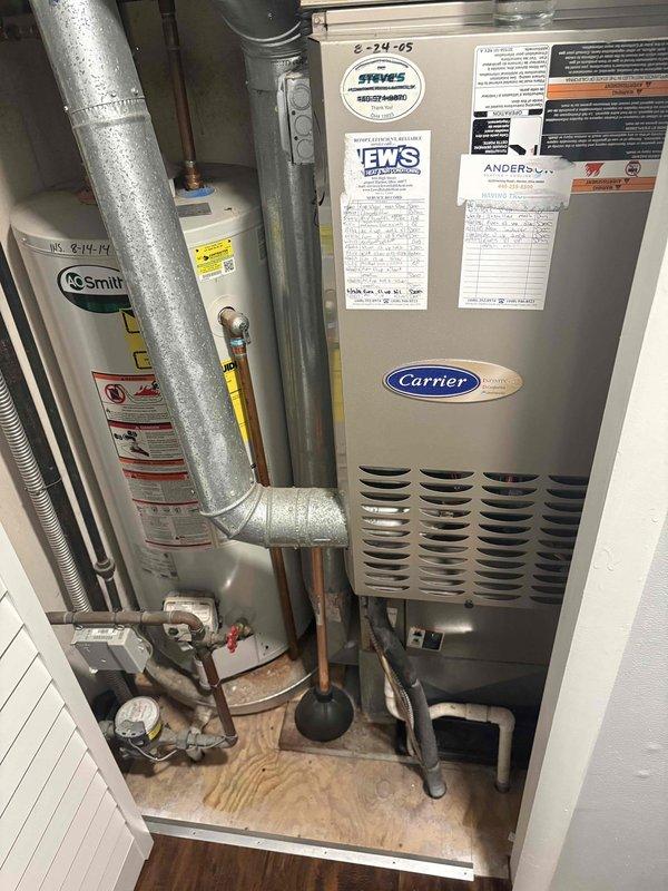 Conducted comprehensive assessment of existing residential HVAC system for replacement estimate. Inspected Carrier air handler unit installed in utility closet alongside A.O. Smith water heater. Evaluated current equipment configuration, ductwork connections, thermostat wiring, and mechanical room layout. Documented equipment conditions, control wiring setup with multiple colored conductors, and existing duct platform installation. Photographed system components and utility space to prepare accurate replacement quote specifications for new air conditioning system installation.