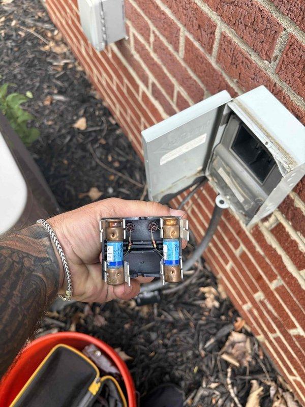 Completed cooling maintenance club visit on air handler system. Performed electrical diagnostics using digital multimeter, measuring voltage at dual fuse block assembly mounted on exterior brick wall near electrical junction box. Verified proper electrical readings of 47.7 volts and inspected fuse connections for secure contact and proper operation. Conducted standard preventive maintenance procedures on cooling system components including visual inspection of capacitor and associated mechanical equipment to ensure optimal performance for the upcoming cooling season.