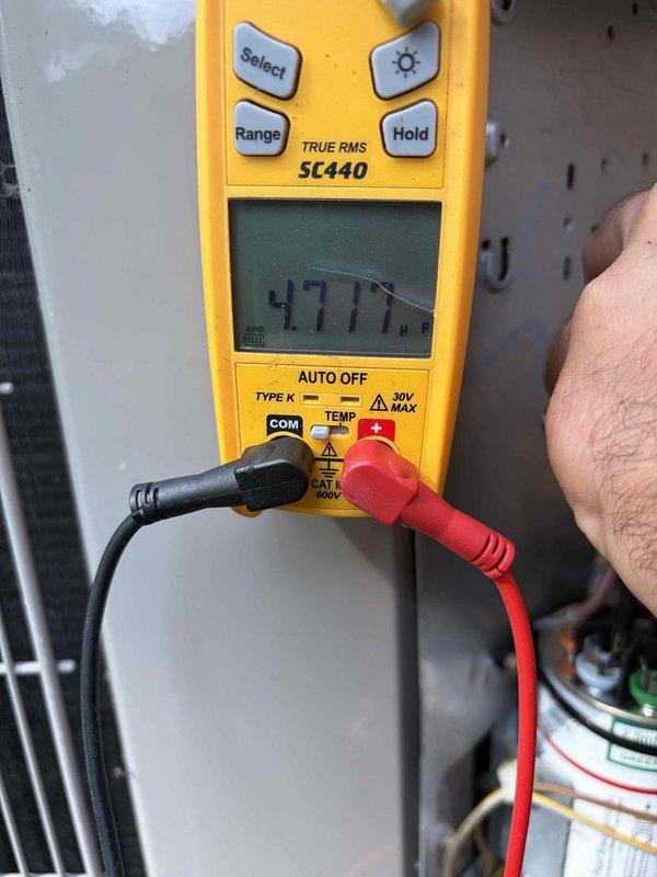 Completed cooling maintenance club visit on air handler system. Performed electrical diagnostics using digital multimeter, measuring voltage at dual fuse block assembly mounted on exterior brick wall near electrical junction box. Verified proper electrical readings of 47.7 volts and inspected fuse connections for secure contact and proper operation. Conducted standard preventive maintenance procedures on cooling system components including visual inspection of capacitor and associated mechanical equipment to ensure optimal performance for the upcoming cooling season.