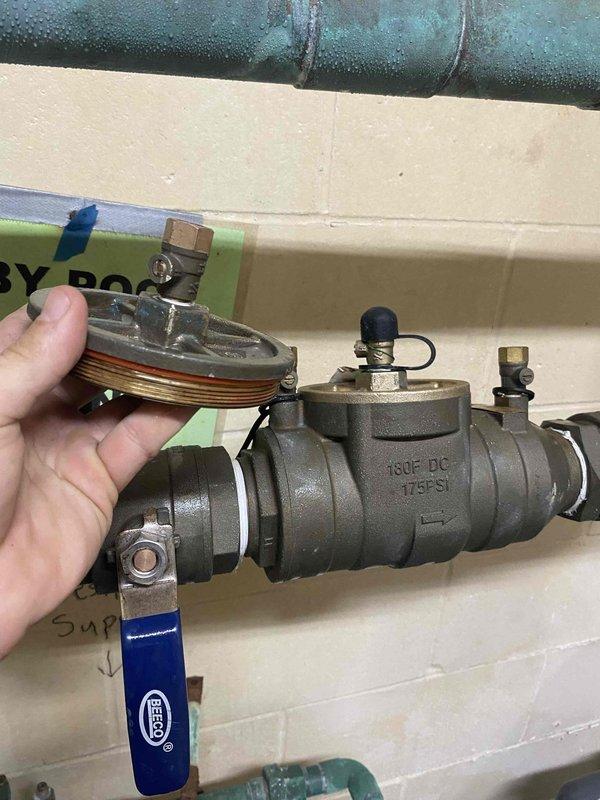 Completed installation of backflow prevention assembly and expansion tank in mechanical room utility space. The work included mounting a new pressure-rated backflow preventer (175 PSI rated) with dual isolation ball valves, installing a floor-mounted expansion tank with proper connections to the fresh cold water supply line, and addressing water pooling issues observed in the area. All components were secured according to plumbing code requirements with appropriate pipe supports and brackets.