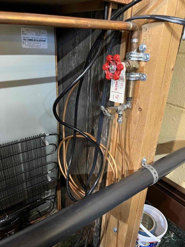 Installed water supply connection for ice maker using copper tubing and compression fittings. Mounted red-handled shut-off valve on chrome fittings to provide dedicated water line control. Routed copper supply line through existing framing and connected to main water supply, ensuring proper support and clearance from electrical components. Tested system for leaks and verified proper water flow to ice maker connection point.