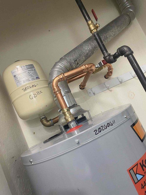 Completed return visit to inspect and verify proper operation of recently installed 40-gallon residential water heater with insulated blanket. Upon arrival, performed comprehensive system check of the new water heater installation, including all water supply connections, gas line connections, and safety components. Verified proper installation of expansion tank with secure mounting and correct piping configuration. Inspected all copper pipe connections with brass fittings for proper assembly and absence of leaks. Confirmed appropriate placement and function of shut-off valves throughout the system. 

Tested water heater ignition sequence and observed combustion chamber operation to ensure proper flame characteristics with blue base indicating complete gas combustion. Verified temperature and pressure relief valve installation and functionality. Confirmed all code-compliant safety measures were in place and operational. System demonstrated proper heating performance with no issues detec