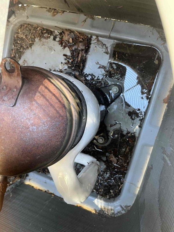 Responded to no cooling complaint on Weathermaker 9200 system circulating lukewarm air. Upon inspection, discovered severely clogged condensate drain pan with extensive organic debris accumulation, decomposed vegetation, and standing water with black sludge. Condensate pump assembly showed heavy rust corrosion throughout cylindrical housing. Float switch mechanism was compromised by debris obstruction. Thoroughly cleaned drain pan, removed all organic matter and sediment buildup, cleared condensate drain lines, and verified proper drainage flow. Replaced corroded condensate pump assembly and tested float switch operation. Confirmed system returned to normal cooling operation with proper condensate removal functionality restored.