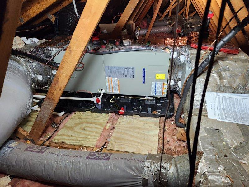 Completed full HVAC system installation including new air handler unit mounted on plywood platform in attic space with proper support structure and insulation placement. Installed outdoor condensing unit with electrical disconnect panel, circuit breakers, and proper voltage wiring to support 17 SEER system operation. Connected refrigerant lines, flexible ductwork with reflective insulation, and all necessary electrical conduit between indoor and outdoor components to establish complete heating and cooling system functionality.