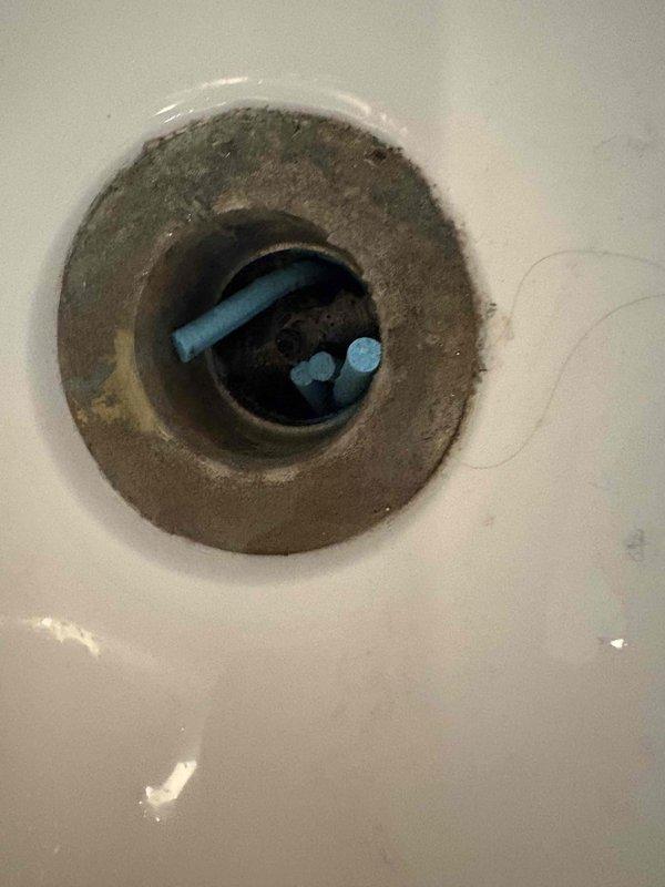 Responded to a clogged bathtub drain backup. Removed drain cover and extracted significant accumulation of hair, debris, and foreign objects including blue plastic fragments from the drain assembly. Cleared blockage, cleaned drain opening of residue buildup, and tested drainage flow to ensure proper operation was restored.