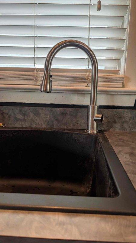 Replaced customer-supplied kitchen faucet with modern pull-down style unit featuring curved spout design and matte black finish. Installed faucet onto undermount sink, ensured proper water flow and spray head functionality, and verified all connections were secure with no leaks detected upon testing.