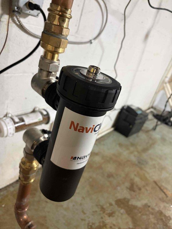 Performed routine maintenance tune-up on boiler system less than one year old. Inspected and addressed reported leak at water filter assembly, which showed signs of moisture at connection points. Examined copper piping, brass fittings, and PVC connections throughout the system, verifying all joints and couplings for proper sealing. Checked filter housing with pressure gauge monitoring device and confirmed all compression fittings were secure. System currently operating within normal parameters with no active leaks detected at time of service completion.