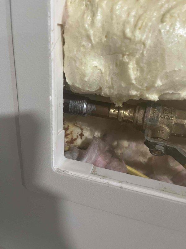 Accessed interior wall cavity to locate and repair leaking outdoor hose bib connection that was causing water intrusion inside the residence. Identified compromised threaded pipe fitting behind exterior wall, tightened connection, and verified leak was stopped. Sealed access panel upon completion of repair.