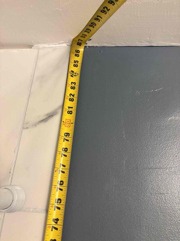 Responded to master bathroom bathtub drain leak in 1970s-era condominium. Performed comprehensive assessment of drain assembly, overflow plate, and spout connections. Took measurements of existing tub configuration and documented current fixture placement to evaluate repair feasibility versus potential walk-in shower conversion. Inspected underside access points and determined extent of work required, noting that drain repair may necessitate floor removal due to limited access in condo construction. Photographed existing conditions including chrome drain cover, overflow assembly, and surrounding marble-pattern tile work for warranty review and future reference.