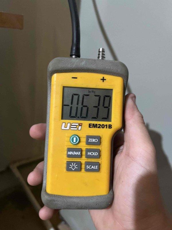 Completed cooling maintenance for club member. Performed system inspection and accessed air handler unit, where accumulated debris and dust buildup was observed in the drain pan area and interior compartment. Took pressure readings using calibrated digital manometer, which displayed -0.639 units, indicating proper negative pressure in the system. Documented equipment condition through photos for maintenance records.
