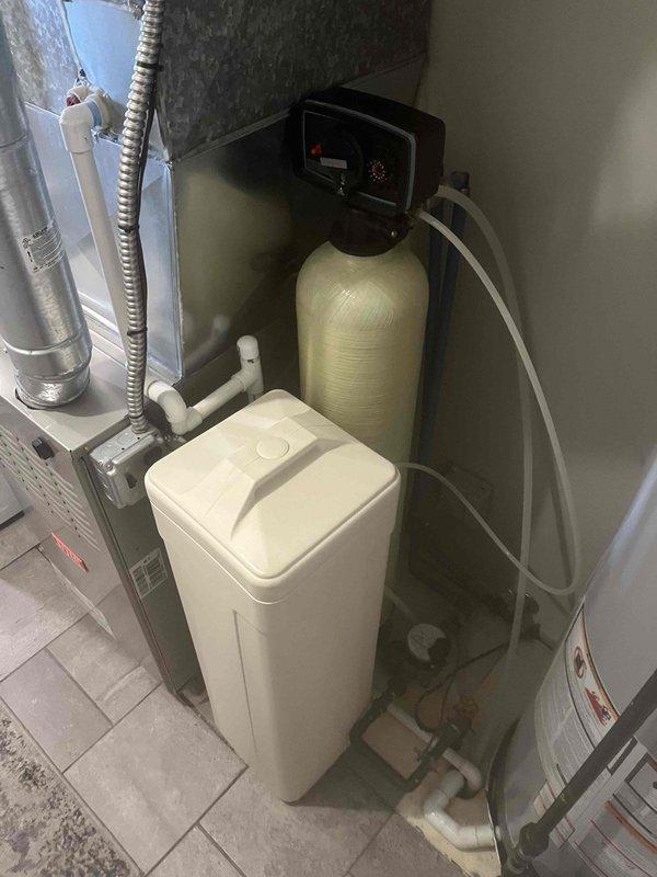 Responded to service call for water softener producing loud ticking noise. Upon inspection of mechanical room, diagnosed issue with control valve on water softener system. Serviced unit by cleaning and lubricating valve mechanism, adjusted regeneration cycle timing, and verified proper operation of all system components. Unit tested successfully with no abnormal sounds present after repair.
