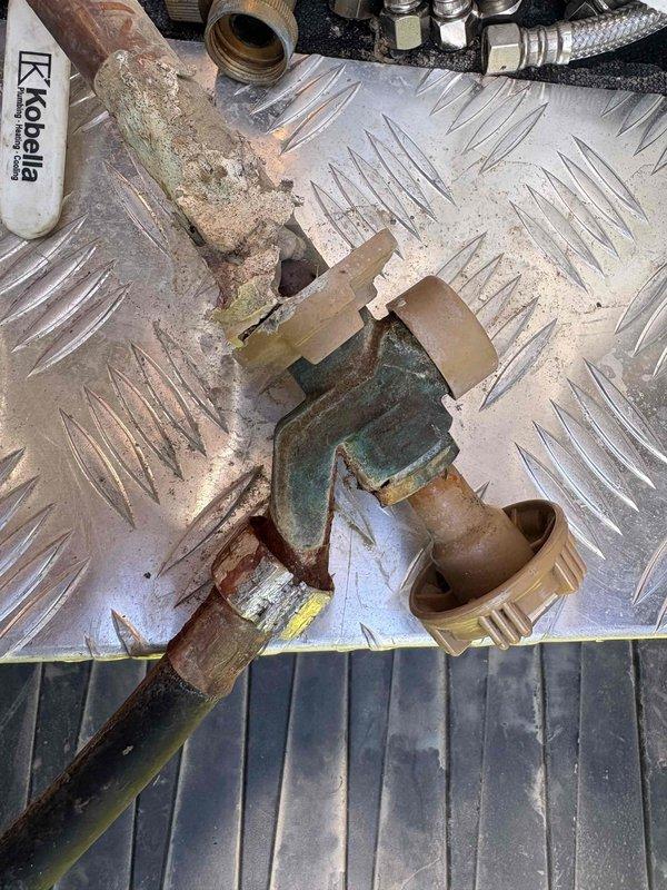 Responded to outdoor water spigot leak on east side of duplex caused by frozen hose attachment. Removed and replaced severely corroded hose bib assembly showing extensive oxidation, mineral buildup, and compromised copper piping connections. Installed new frost-proof sillcock with proper valve seat and threading to prevent future freeze damage.