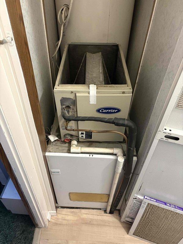 Completed site assessment for full HVAC system replacement in 1500 sq ft mobile home. Evaluated existing Carrier air handler and furnace installation in confined utility closet with water heater. Prepared estimate for replacement of both heating and cooling systems with new 15kW electric furnace and 2.5 ton air conditioning unit. Assessment included evaluation of current vertical stacked configuration, existing ductwork connections, PVC condensate drain lines, and electrical service requirements. Recommended thermostat relocation to optimize placement closer to equipment for improved system control and accessibility.