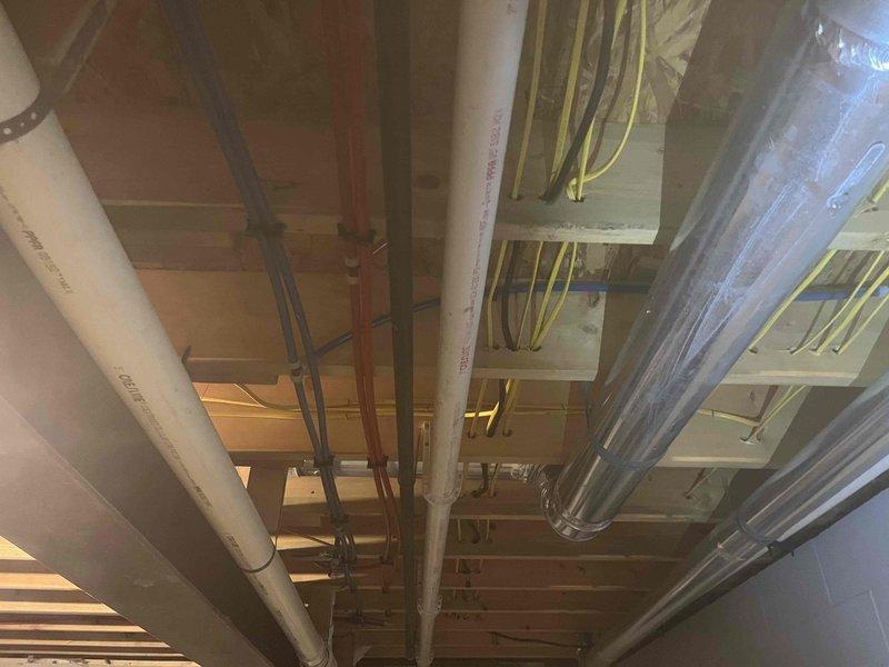 Completed free estimate for garage sink installation requiring new drain line and water supply rerouting. Assessed existing ceiling-mounted plumbing infrastructure including PVC drain lines, copper water supply lines, and utility routing through exposed joists. Evaluated basement access points and existing mechanical systems to determine optimal path for extending water supply and establishing proper drainage connection to main waste line.