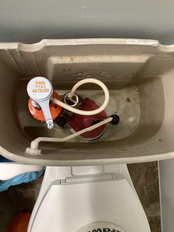 Responded to service call for non-functioning toilet and clogged tub in bathroom. Upon inspection, removed toilet tank lid and assessed internal flushing mechanisms including flush valve assembly and fill valve components. Documented existing condition of tank interior showing mineral deposits and wear on porcelain surfaces. Inspected Kobella brand fill valve system and associated float mechanism for proper operation and water flow. Captured photographic documentation of tank components and hardware configuration for service records.