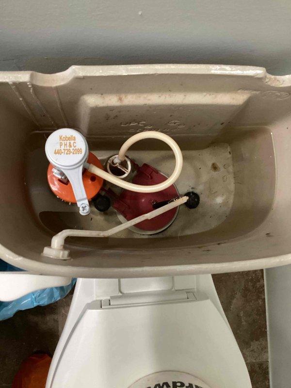 Responded to service call for non-functioning toilet and clogged tub in bathroom. Upon inspection, removed toilet tank lid and assessed internal flushing mechanisms including flush valve assembly and fill valve components. Documented existing condition of tank interior showing mineral deposits and wear on porcelain surfaces. Inspected Kobella brand fill valve system and associated float mechanism for proper operation and water flow. Captured photographic documentation of tank components and hardware configuration for service records.