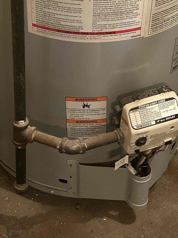Responded to water leak at boiler/plumbing connection point. Upon arrival, inspected water heater tank base and identified moisture accumulation on concrete floor near copper pipe connections and gas control valve assembly. Utilized diagnostic temperature probe to assess system conditions and verify leak source at the interface between plumbing lines and water heater unit. Documented equipment condition including gas control valve assembly, copper piping connections, and warning labels for service records.