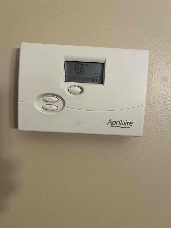 Completed HVAC club membership enrollment and performed system documentation. Inspected and photographed Aprilaire thermostat showing proper operation with display readings of 65° and 60°. Documented return air grate condition in mechanical space, noting standard installation with exposed framing in utility area.