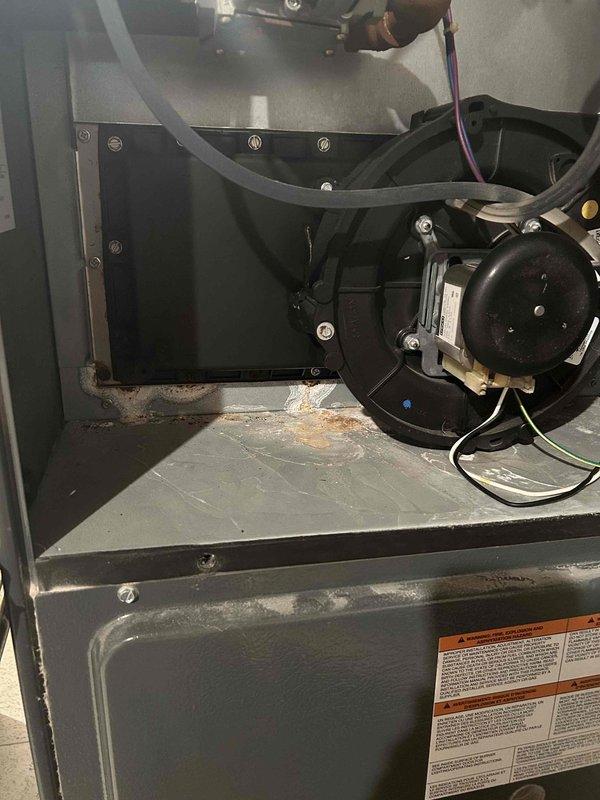 Responded to no heat call on furnace blowing cold air. Upon inspection, found system equipped with old-style mechanical thermostat. Performed diagnostic evaluation of heating system, inspecting blower motor assembly, ductwork connections, and internal components for proper operation. Addressed airflow concerns and verified all mechanical connections within the cabinet were secure. System showed normal wear with dust and debris accumulation on base platform, which is typical for operational equipment. Confirmed all safety labels and warning indicators were visible and intact per code requirements.