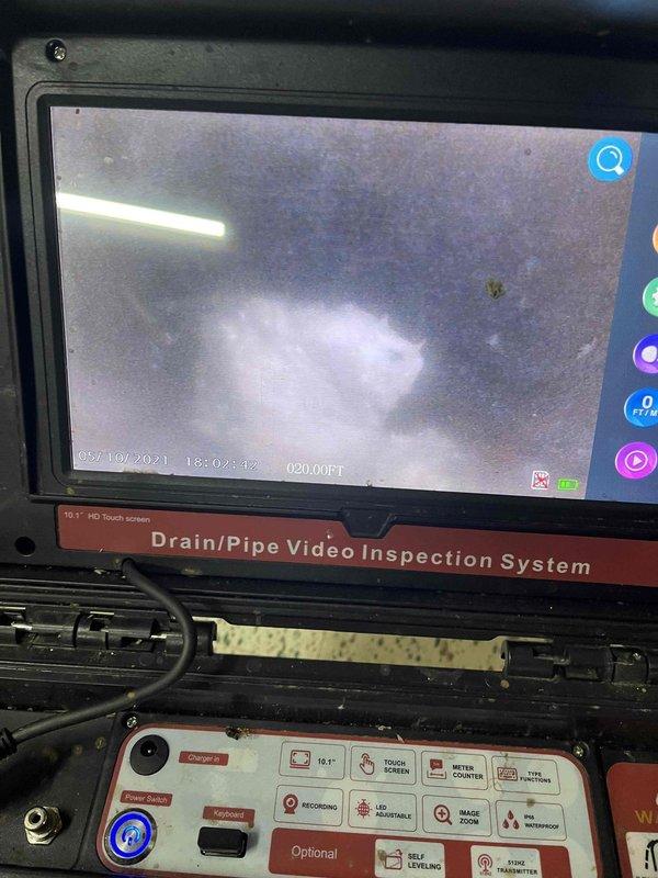 Responded to a slow-draining laundry drain complaint. Performed video camera inspection of the drain line, advancing the camera approximately 20 feet into the system to identify the cause of the backup. Inspection revealed accumulated sludge and debris within the pipe causing restricted flow. The drain line, consisting of white PVC piping with floor penetration in a terrazzo-floored area, was successfully assessed and the blockage location documented for clearing.