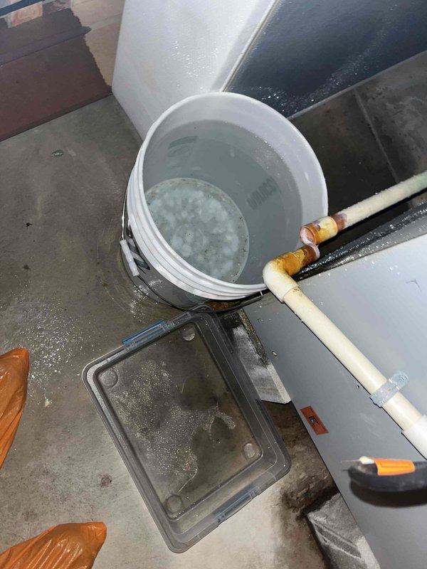Responded to callback for recurring water leak at air handler. Upon inspection, found condensate drain line system experiencing drainage issues with standing water in collection bucket and moisture present on unit surfaces. Cleared blockage in condensate line, verified proper operation of float switch safety mechanism, and tested drain flow. Confirmed PVC condensate piping and compression fittings secure with no leaks. System now draining properly with float switch functioning as designed.