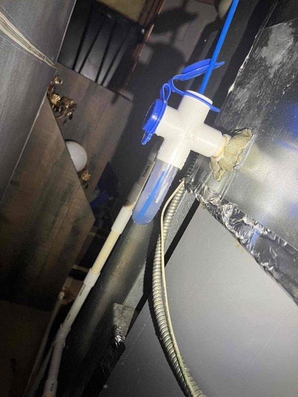 Responded to callback for recurring water leak at air handler. Upon inspection, found condensate drain line system experiencing drainage issues with standing water in collection bucket and moisture present on unit surfaces. Cleared blockage in condensate line, verified proper operation of float switch safety mechanism, and tested drain flow. Confirmed PVC condensate piping and compression fittings secure with no leaks. System now draining properly with float switch functioning as designed.