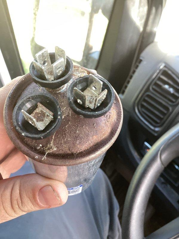 # HVAC Service Report

Responded to no cooling complaint on residential air conditioning system over 10 years old. Upon inspection, identified failed dual run capacitor with severe corrosion on terminals and visible oxidation damage. Capacitor showed brown-orange patina indicating extended exposure to environmental elements and complete failure. Removed defective capacitor from outdoor condensing unit and replaced with new OEM-equivalent dual run capacitor properly rated for system specifications. Verified all electrical connections were secure and torqued to manufacturer standards. Tested system operation and confirmed compressor and condenser fan motor startup with proper amperage draw. System restored to normal cooling operation. Advised customer of system age and recommended monitoring for additional component wear.