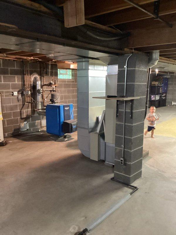 Conducted on-site assessment for complete HVAC system replacement in residential property. Existing air conditioning unit was evaluated and determined to be beyond economical repair, requiring full system replacement. Inspected basement installation area housing current furnace/air handler unit and existing ductwork infrastructure. Documented current system configuration including metal cabinet air handler, black flexible and rigid ductwork distribution throughout exposed ceiling joists, and concrete block foundation construction. Evaluated existing thermostat wiring and control system for compatibility with new equipment installation. Photographed equipment locations, mechanical room layout, ductwork pathways, and structural considerations for replacement system sizing and installation planning. Provided comprehensive estimate for new air conditioning system installation.