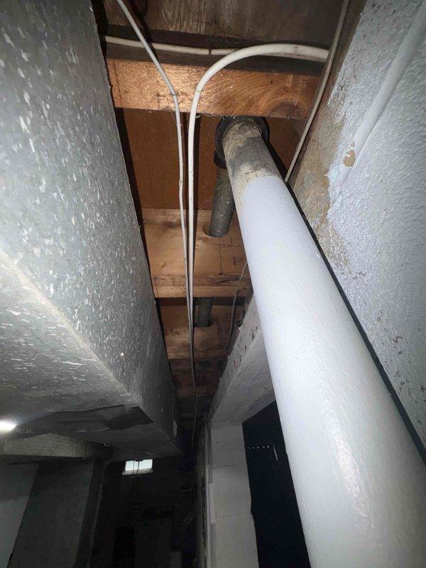 Performed comprehensive plumbing assessment of bathtub drainage system experiencing code violations and active water leakage into basement. Inspection revealed severely corroded cast iron waste piping with compromised threaded connections and deteriorated elbow fittings exhibiting advanced oxidation throughout the drain assembly. Documented existing illegal plumbing configuration preventing proper drainage, including improperly installed PVC transition connections with inadequate rubber couplings in ceiling cavity. Provided detailed photographic documentation of corroded metallic piping requiring complete replacement and recommended full remediation of non-compliant drainage system to restore proper function and prevent continued water damage to basement area.