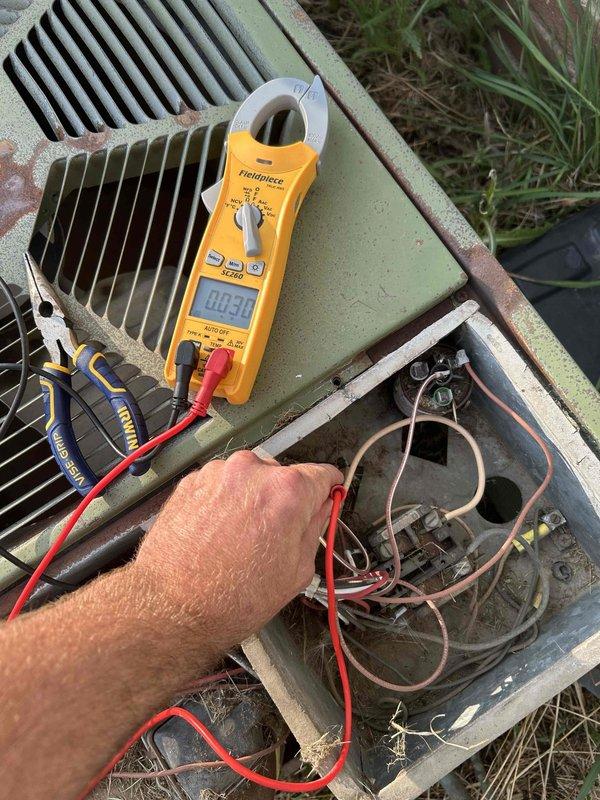 Responded to no cooling complaint where outdoor unit was clicking but not running. Performed electrical diagnostics on outdoor condensing unit using digital multimeter to test voltage and amperage at contactor and electrical connections. Measured 252 volts at control box terminals. Inspected weathered electrical compartment and wiring connections. Tested system operation and verified proper electrical supply to unit components.
