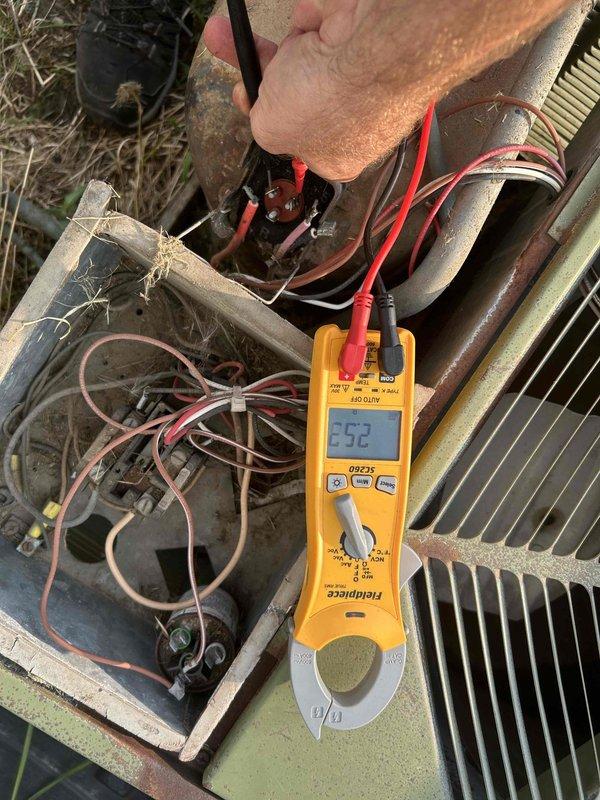 Responded to no cooling complaint where outdoor unit was clicking but not running. Performed electrical diagnostics on outdoor condensing unit using digital multimeter to test voltage and amperage at contactor and electrical connections. Measured 252 volts at control box terminals. Inspected weathered electrical compartment and wiring connections. Tested system operation and verified proper electrical supply to unit components.