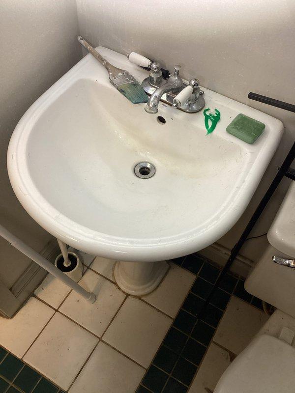 Responded to service call for gray water issue at bathroom sink. Inspected plumbing connections beneath pedestal sink and confirmed water discoloration present. Equipment identified as Kinetiko brand water treatment system, less than five years old, not originally installed by our company. Documented existing conditions with photographs showing sink fixtures, supply lines, shut-off valve, and cabinet interior with visible water staining on floor surface. Applied promotional coupon for non-proprietary equipment service.
