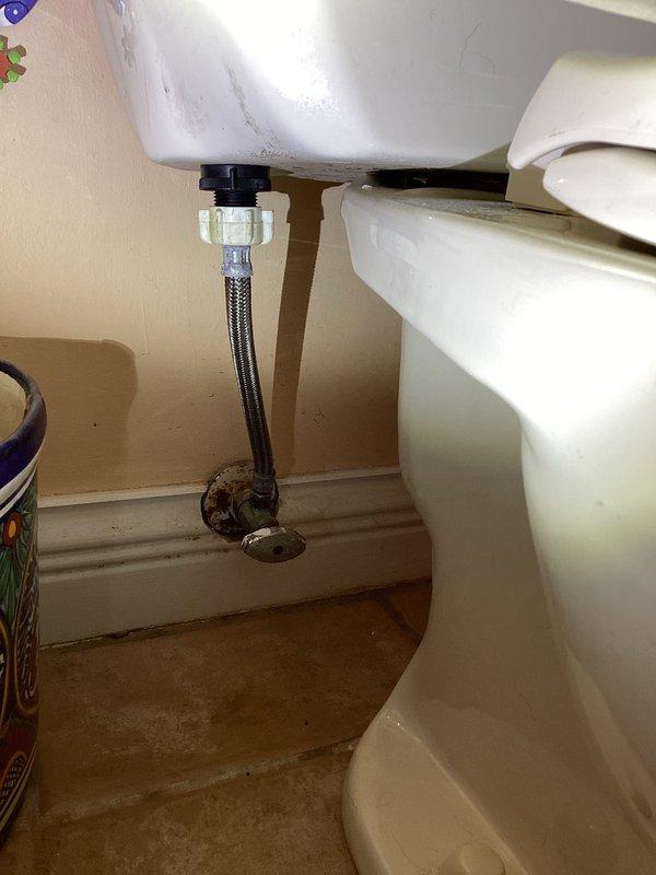 Responded to service call for gray water issue at bathroom sink. Inspected plumbing connections beneath pedestal sink and confirmed water discoloration present. Equipment identified as Kinetiko brand water treatment system, less than five years old, not originally installed by our company. Documented existing conditions with photographs showing sink fixtures, supply lines, shut-off valve, and cabinet interior with visible water staining on floor surface. Applied promotional coupon for non-proprietary equipment service.