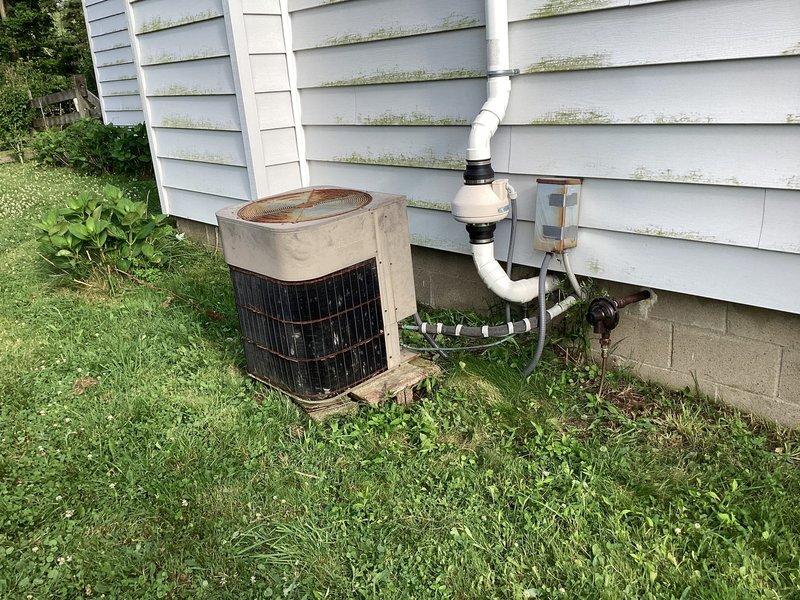 Conducted HVAC system evaluation following capacitor replacement that failed to resolve operational issues. Assessed aging outdoor condensing unit showing significant weathering, rust staining on top panel, and overall deterioration consistent with end-of-service-life condition. Evaluated indoor air handler in basement mechanical room and complete system performance. Presented equipment replacement options and buyback programs to address failing system components and prevent complete system failure.