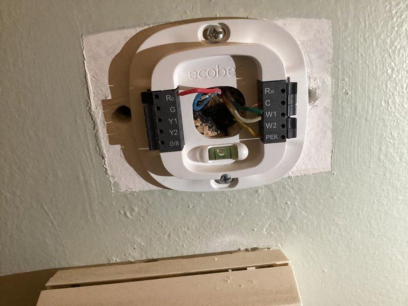 Completed HVAC system evaluation for equipment replacement estimate. Assessed existing outdoor condensing unit positioned against exterior brick wall and documented current ecobee smart thermostat installation with multi-stage wiring configuration including Rc, C, Y1, Y2, O/B, Rh, W1, W2, and PEK terminals to determine compatibility requirements for proposed replacement system.
