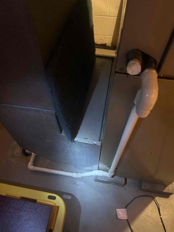 Completed comprehensive AC tune-up on residential HVAC system located in basement utility area. Performed standard maintenance protocol including inspection of electrical components, contactors, and capacitor within control panel, noting significant dust and debris accumulation with visible corrosion on mounting surfaces. Verified proper operation of condensate drain lines and PVC piping system routing from unit across floor area.