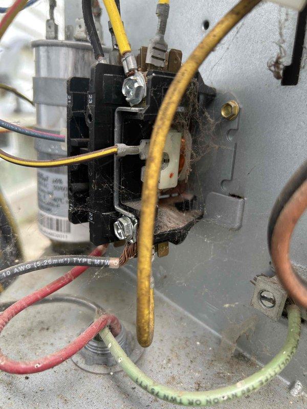 Completed comprehensive AC tune-up on residential HVAC system located in basement utility area. Performed standard maintenance protocol including inspection of electrical components, contactors, and capacitor within control panel, noting significant dust and debris accumulation with visible corrosion on mounting surfaces. Verified proper operation of condensate drain lines and PVC piping system routing from unit across floor area.