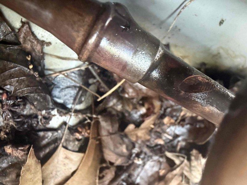 Responded to service call for attic-mounted air conditioning unit with non-operational condenser fan. Upon inspection, diagnosed failed dual run capacitor preventing fan motor operation. Replaced defective capacitor with manufacturer-specified component, restored proper fan function, and verified system cooling performance. Noted moderate debris accumulation around outdoor coil and copper refrigerant lines showing normal condensation during operation; recommended routine maintenance to prevent future airflow restrictions.