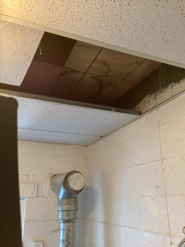 Conducted comprehensive assessment of existing ductwork system in commercial space for boiler heating distribution. Evaluated flexible aluminum duct installation running vertically along concrete block wall with elbow transition to ceiling plenum. Documented measurements of galvanized metal ductwork components, including 10-inch vertical section with elbow joint transitioning to horizontal run. Identified water damage in ceiling plenum affecting multiple acoustic tiles, indicating potential moisture infiltration requiring remediation. Assessed condition of sheet metal connections, fasteners, and overall duct integrity to provide accurate estimate for ductwork replacement or modification to support boiler heating system requirements.