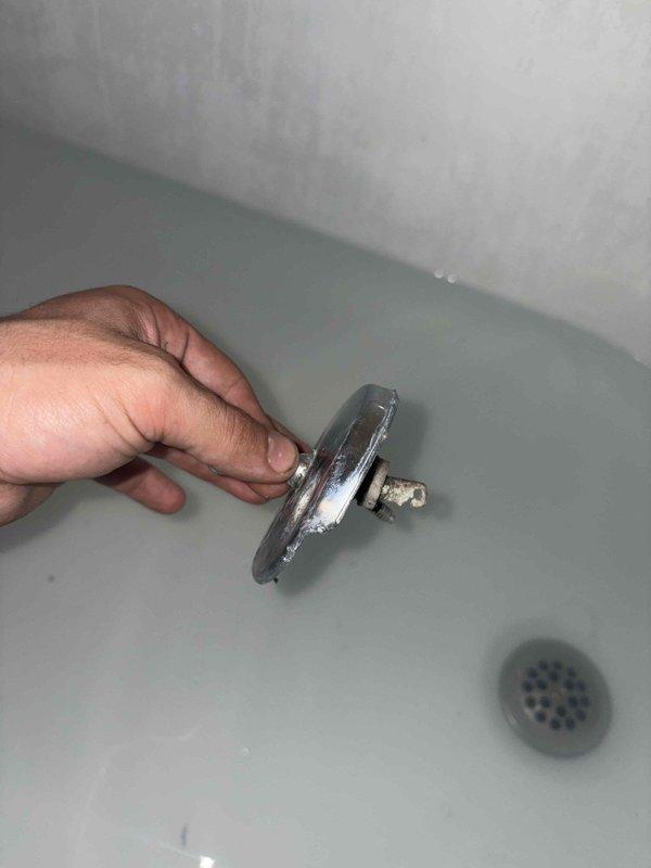 Responded to emergency plumbing call for shower drain blockage and toilet squealing issue. Upon inspection, found severely corroded bathtub overflow plate and drain assembly with heavy mineral buildup and deterioration affecting drainage. Cleared obstruction from shower drain line, removed and cleaned corroded overflow cover showing significant chrome plating failure and rust accumulation. Addressed toilet fill valve issue causing squealing noise during flush cycle. Restored proper drainage function to shower and eliminated toilet noise to ensure facilities were operational for immediate use.