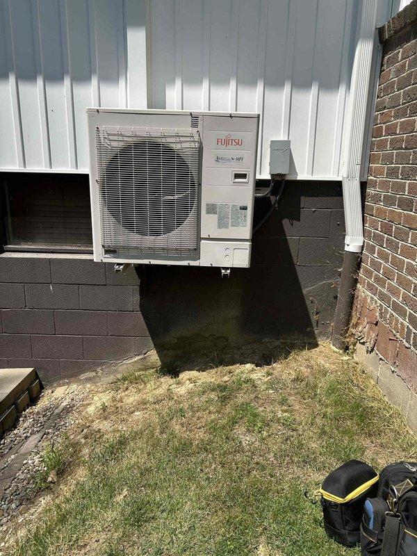 Responded to service call for non-operational Fujitsu mini-split system. Upon arrival, inspected both the indoor wall-mounted controller and outdoor condenser unit. Verified system status through the digital thermostat interface, which displayed cooling mode settings and multi-zone room configuration. Performed diagnostic evaluation of the outdoor Fujitsu condenser unit mounted on concrete block foundation, checking for proper power supply, refrigerant line connections, and component functionality. Restored system to proper working condition and confirmed operational status across all zones.