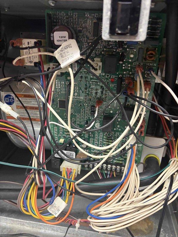Responded to no cooling call with thermostat display failure. Upon arrival, found Aprilaire control unit with blank display despite hardwired power connection. Inspected control board and wiring connections, verified multiple LED indicators illuminated on circuit board, and assessed internal components including terminal blocks, fuses, and 120V igniter circuit. Documented system configuration and wiring arrangement for HVAC control system diagnostics.
