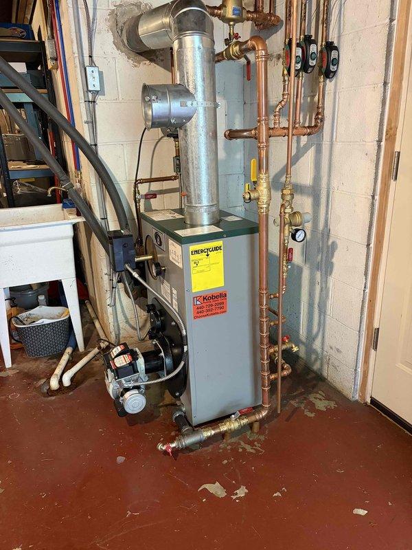 Completed installation of new boiler system with hydronic heating configuration. Installed Kobella water heater unit with galvanized exhaust venting through existing wall penetration. Configured extensive copper piping network with multiple zones, incorporating three circulation pumps for heat distribution throughout the residence. Installed brass valves, pressure relief components, and shutoff mechanisms with proper gauging for system monitoring. Connected base-mounted circulation pump with flexible hoses for system operation. All soldered joints completed to code, system pressurized and tested for proper operation across all zones. Air handler maintenance has been scheduled for follow-up service.