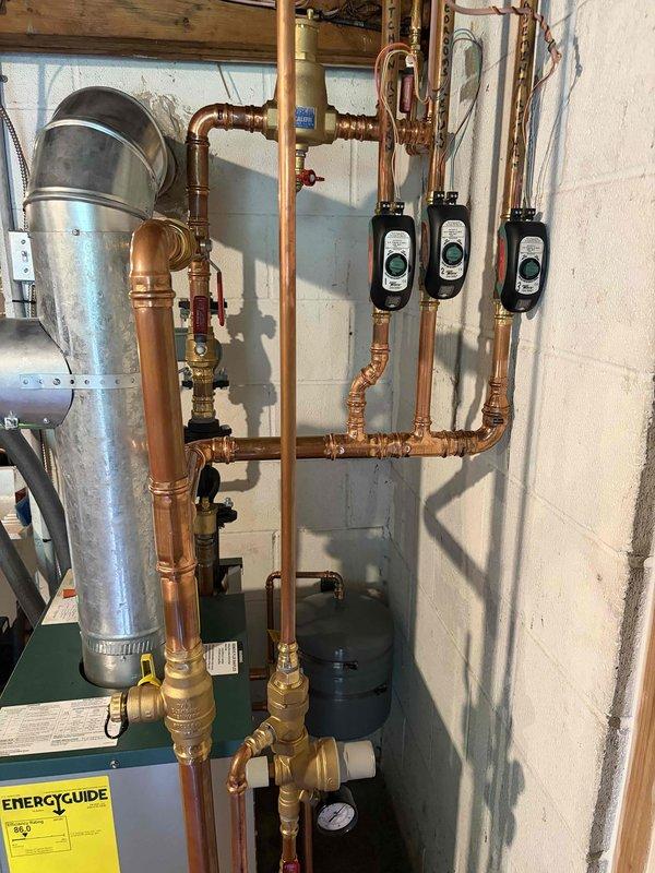 Completed installation of new boiler system with hydronic heating configuration. Installed Kobella water heater unit with galvanized exhaust venting through existing wall penetration. Configured extensive copper piping network with multiple zones, incorporating three circulation pumps for heat distribution throughout the residence. Installed brass valves, pressure relief components, and shutoff mechanisms with proper gauging for system monitoring. Connected base-mounted circulation pump with flexible hoses for system operation. All soldered joints completed to code, system pressurized and tested for proper operation across all zones. Air handler maintenance has been scheduled for follow-up service.