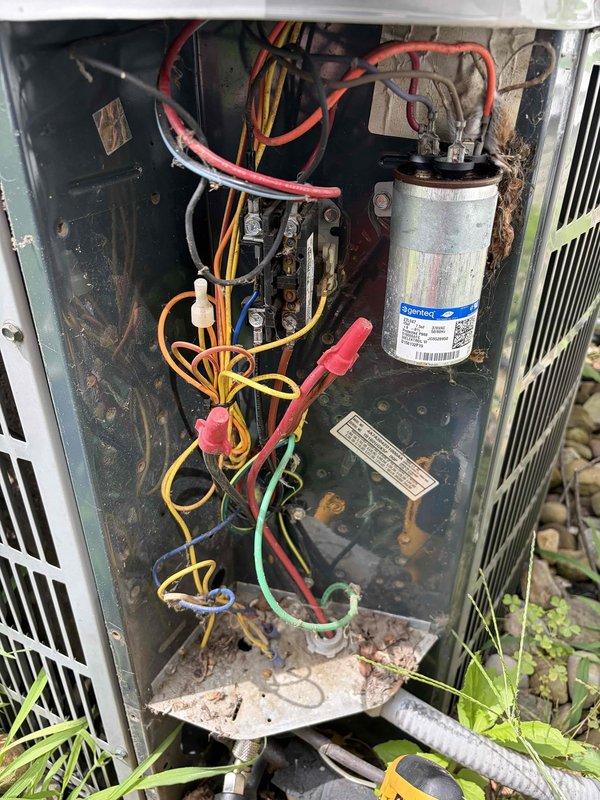 # HVAC Service Report

Responded to service call for reported furnace leak. Upon inspection, discovered unit was actually an outdoor heat pump/air conditioning condenser, not a furnace. Removed access panel to assess interior components and identify source of moisture concern. Found capacitor, contactor, and electrical connections intact but unit interior showed significant accumulation of leaves, organic debris, and dirt throughout compartment. Observed extensive rust and corrosion on metal housing, base plate, and internal surfaces indicating prolonged exposure to weather and lack of routine maintenance. Documented unit condition with photographs showing deteriorated state of components and debris accumulation. Cleaned debris from around capacitor and electrical components to prevent potential operational issues. Noted vegetation growth around unit base restricting airflow. Verified all electrical connections secure despite corrosion present. Recommended comprehensive cleaning of con