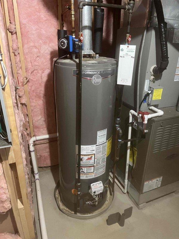 Conducted on-site assessment of existing Rheem Performance Platinum water heater for replacement quotation. Inspected current installation including plumbing connections, venting configuration, and proximity to HVAC equipment in basement utility area. Documented ambient conditions using digital measurement devices, recording temperature and humidity levels to assess environmental factors affecting equipment performance and longevity.