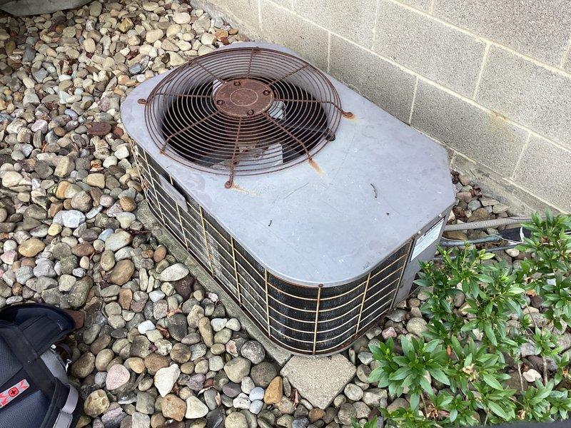 Conducted equipment replacement estimate for 1500 square foot residential property with 30+ year old air conditioning system showing significant weathering, corrosion, and oxidation on condenser unit and fan assembly. Evaluated existing outdoor unit positioned on river rock base against exterior wall, documented deteriorated components including rusted fan housing and grille, and assessed electrical connections with aged conduit and wiring. Provided replacement options and system sizing recommendations for updated HVAC equipment suitable for property specifications.