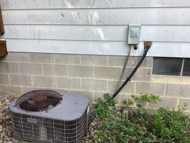 Conducted equipment replacement estimate for 1500 square foot residential property with 30+ year old air conditioning system showing significant weathering, corrosion, and oxidation on condenser unit and fan assembly. Evaluated existing outdoor unit positioned on river rock base against exterior wall, documented deteriorated components including rusted fan housing and grille, and assessed electrical connections with aged conduit and wiring. Provided replacement options and system sizing recommendations for updated HVAC equipment suitable for property specifications.
