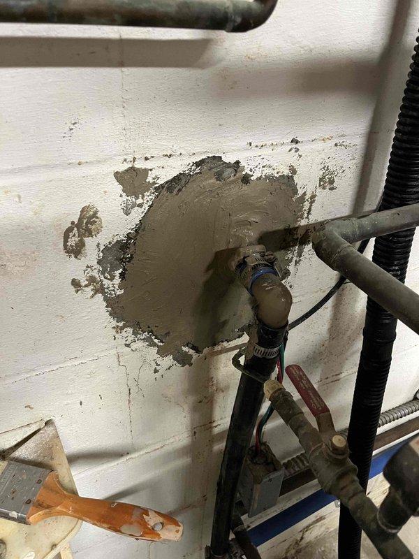 # Plumbing Service Completed

Returned to property to complete hose bib installation that was previously sold and initiated. Upon arrival, assessed existing plumbing configuration featuring aged copper piping with brass manifold connections mounted to exterior wall penetration area. Wall surface showed significant deterioration and damage around pipe penetrations, with exposed substrate material and moisture intrusion evident throughout the work area.

Completed installation of hose bib assembly, making necessary connections to existing copper supply lines through brass manifold system. All pipe connections were properly secured using appropriate fittings and clamps to ensure water-tight seals. Verified proper valve operation and flow control functionality of newly installed hose bib.

Addressed moisture concerns by inspecting all visible piping for leaks and confirming integrity of connections. Noted heavy condensation on wall surfaces and piping components, along with mineral deposit