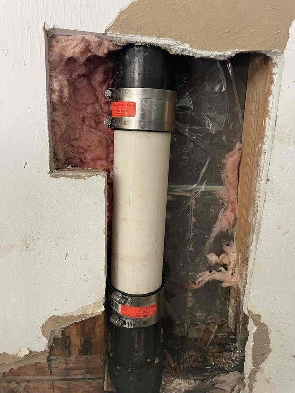 Responded to a leak at the garage sink. Upon investigation, accessed the wall cavity to locate the source of the water intrusion affecting the PVC drain line. Identified leak at pipe connection point, replaced damaged coupling bands, and secured the vertical drain pipe with new metal clamps. Verified proper drainage and confirmed leak was resolved. Wall opening left accessible for drying and future closure by property owner.